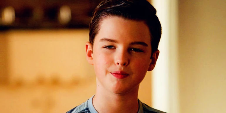 Sheldon smiling as he looks at something in Young Sheldon 