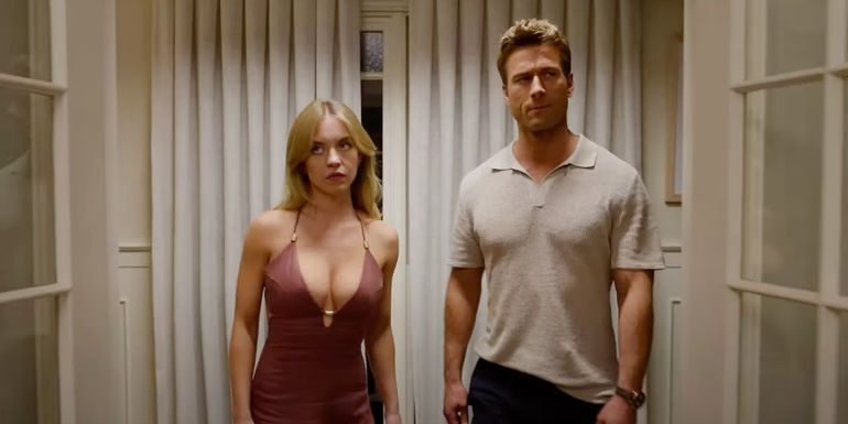 Glen Powell and Sydney Sweeney walking next to each other and looking annoyed in Anyone But You.