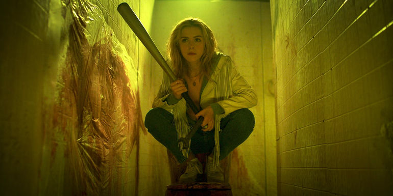 Kiernan Shipka crouching on chair and holding a bat in Totally Killer
