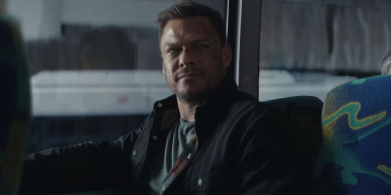 Alan Ritchson as Reacher sitting on the bus