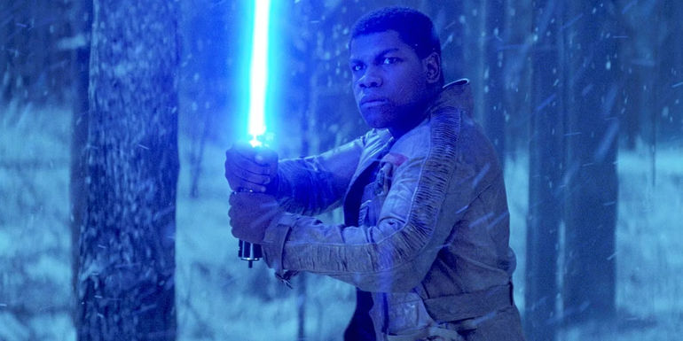 John Boyega as Finn wielding a blue lightsaber in Star Wars The Force Awakens
