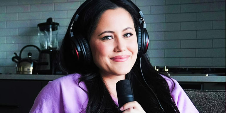 Teen Mom star Jenelle Evans smiles slightly while wearing headphones and holding microphone