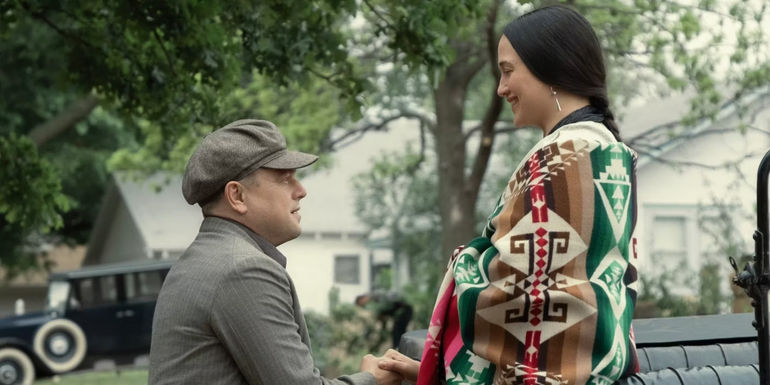 Leonardo DiCaprio as Ernest Burkhart kneeling down in front of Lily Gladstone as Mollie Burkhart in Killers of the Flower Moon