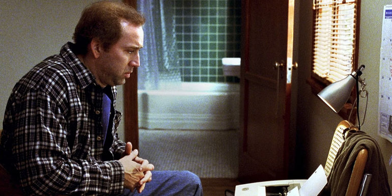 Nicholas Cage sitting down looking pensive in Adaptation.
