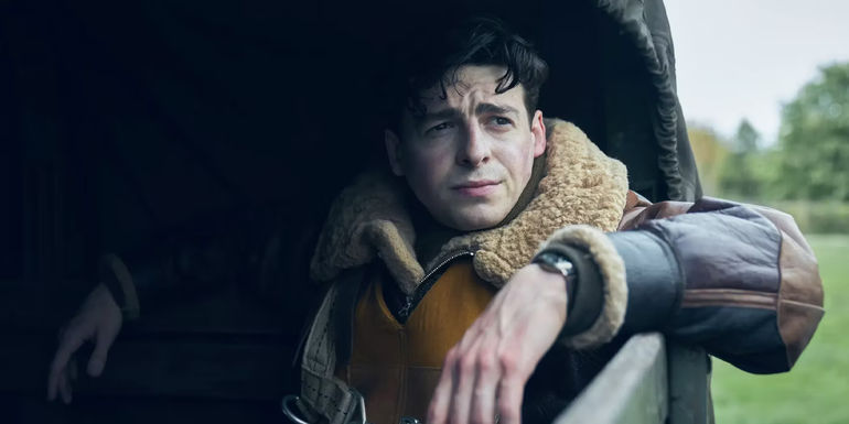 Anthony Boyle as Harry Crosby leaning on a car from Masters of the Air