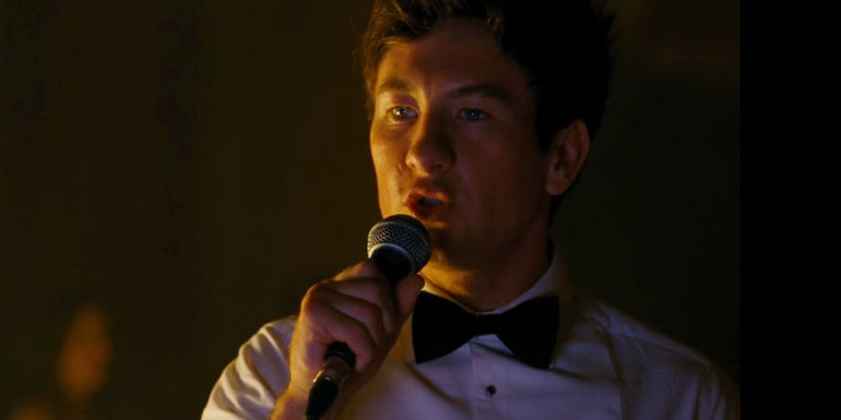 Oliver (Barry Keoghan) wearing a bowtie while singing karaoke in Saltburn.