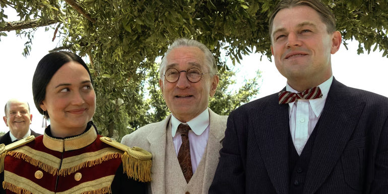 Lily Gladstone, Robert De Niro, and Leonardo DiCaprio smiling together in Killers of the Flower Moon