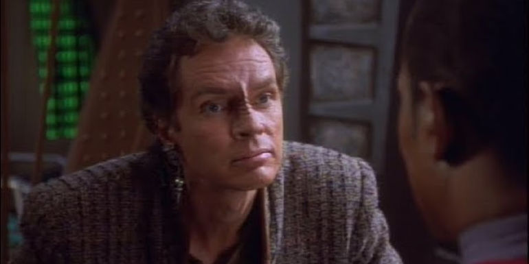 Li Nalas leans forward while telling Sisko a story