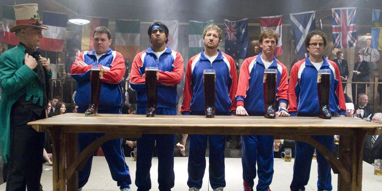 The Broken Lizard cast ready to drink their beer boots as an official in a cap looks on in Beerfest.
