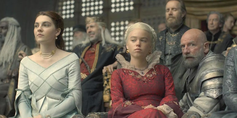Milly Alcock as Rhaenyra in House of the Dragon, sitting at a lavish event, giving a skeptical look