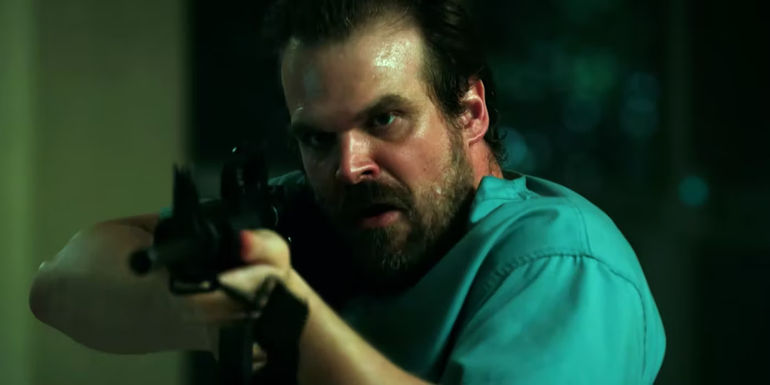 David Harbour as Jim Hopper pointing a gun in Stranger Things season 2