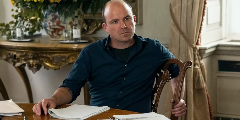 Trowbridge sitting at a table and reading a document in The Diplomat