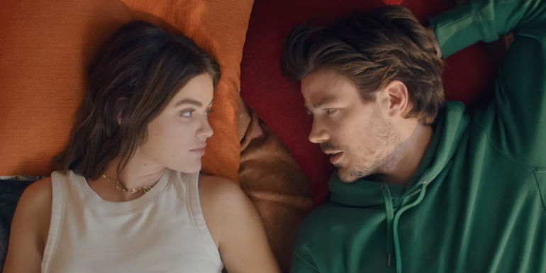 Lucy Hale and Grant Gustin lay in a bed looking at each other in Puppy Love