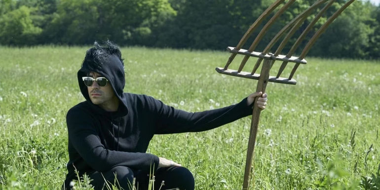 David in a field with a huge pitchfork in Schitt's Creek.