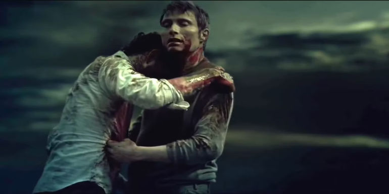 Hugh Dancy as Will Graham and Mads Mikkelsen as Dr. Hannibal Lecter covered in blood and embracing one another in the final scene of Hannibal.