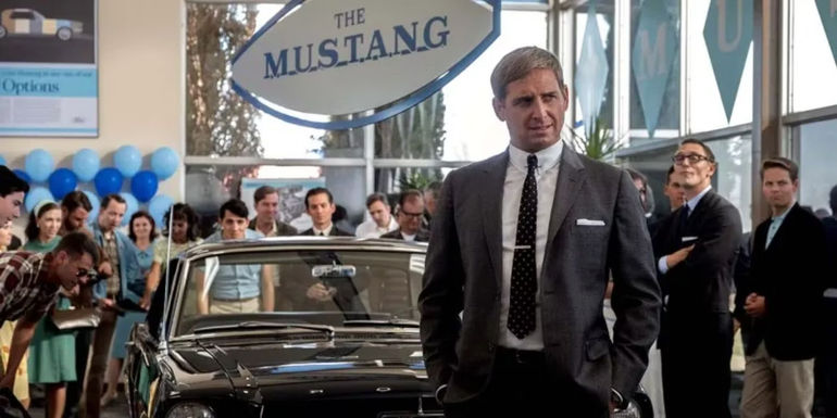 Leo Beebe (Josh Lucas) speaking in front of a group of people surrounding a Ford Mustang in Ford v Ferrari.