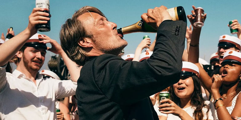 Mads Mikkelsen drinking straight from a wine bottle in Another Round
