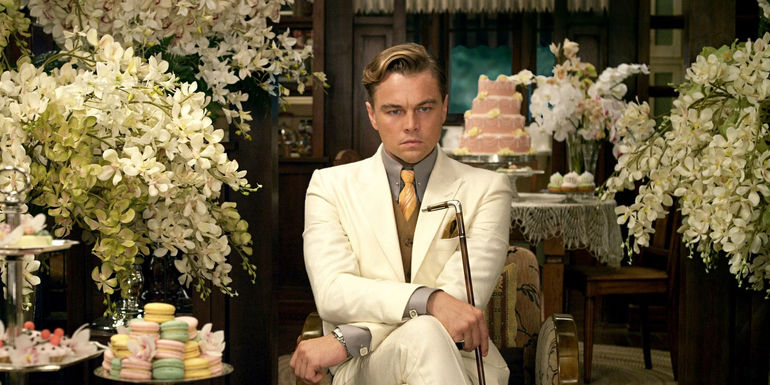 Gatsby (Leonardo DiCaprio) surrounded by flowers and cakes in The Great Gatsby