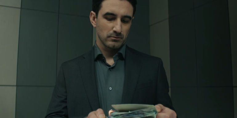 Ferdinand Kingsley as AM burning a passport in an airport bathroom in Reacher