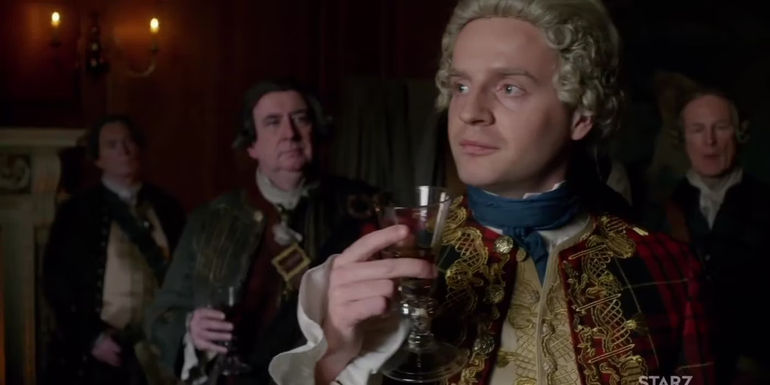 George Murray standing behind Bonnie Prince Charles as he drinks wine in Outlander