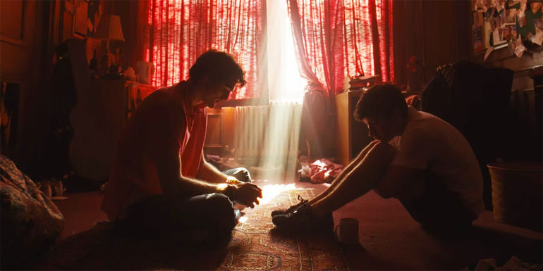 Saltburn Felix and Oliver sitting on the floor at Felix's dorm