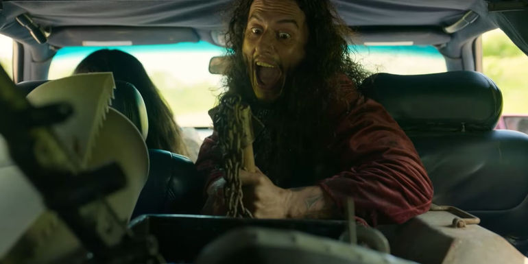 Loud (Richard Cabral) happily holding a weapon in the back of a car in Twisted Metal.