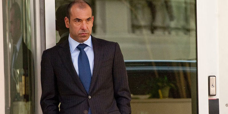 Rick Hoffman as Louis Litt standing in a doorway in Suits