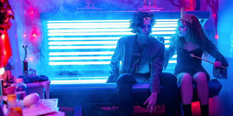 Cole Sprouse as The Creature and Kathryn Newton as Lisa Swallows sitting on the edge of a tanning bed in Lisa Frankenstein