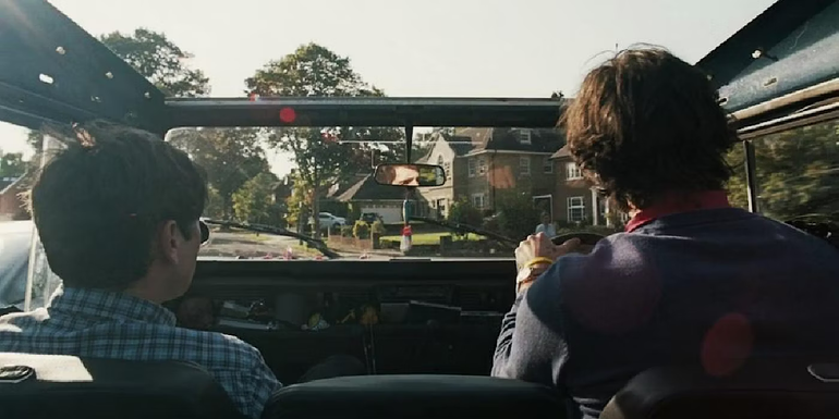 Felix and Oliver driving down a residential street in Saltburn