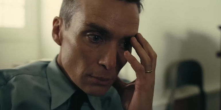 Oppenheimer holds his hand to his face in Oppenheimer.