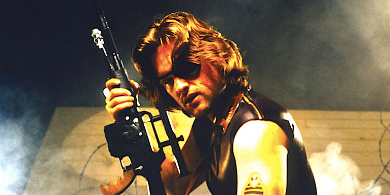 Kurt Russell's Snake Plissken holding a gun as he kneels down in Escape from New York