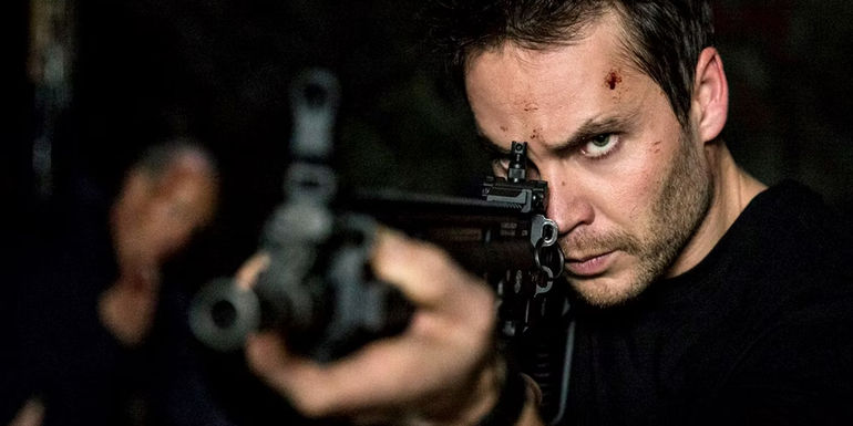 Taylor Kitsch as Ghost pointing an assault rifle in American Assassin