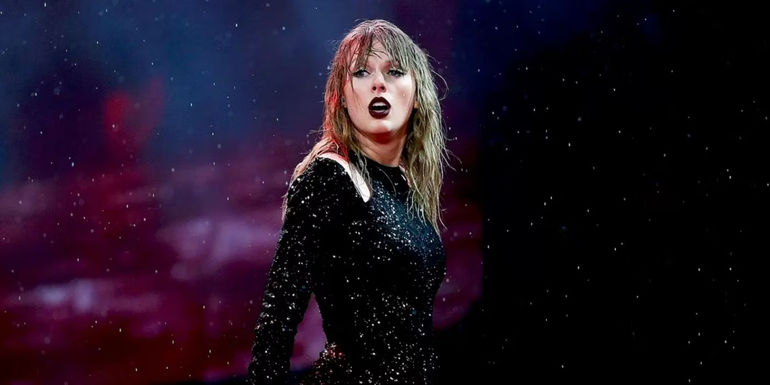 Taylor Swift looking over the crowd in front of a starry backdrop in Taylor Swift Reputation Stadium Tour.