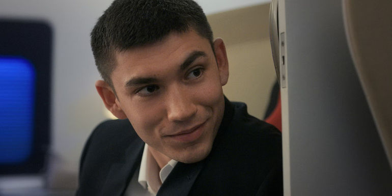 Archie Renaux as William looks behind him on a plane in Upgraded