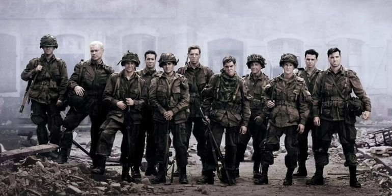 11 soldiers standing next to each other in a battlefield in Band of Brothers