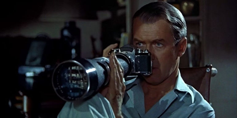 Jeff (James Stewart) holding a camera while peeping at the neighbors in Rear Window