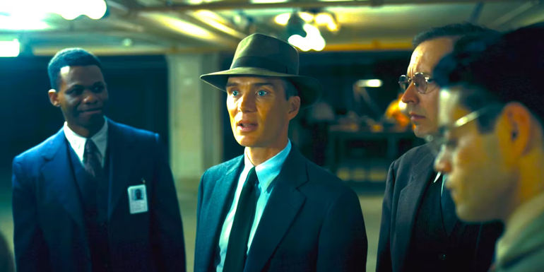 Cillian Murphy as Oppenheimer talking with wide-eyed intensity to a group of men in Oppenheimer