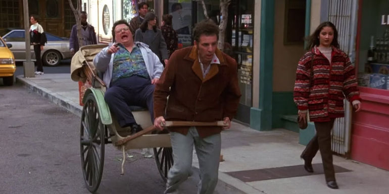 Kramer (Michael Richards) pulls Newman (Wayne Knight) along in a rickshaw in Seinfeld.