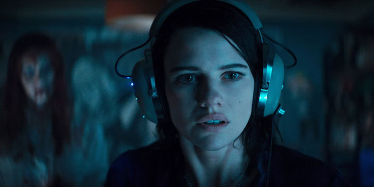 Beth looking surprised while wearing headphones in Evil Dead Rise