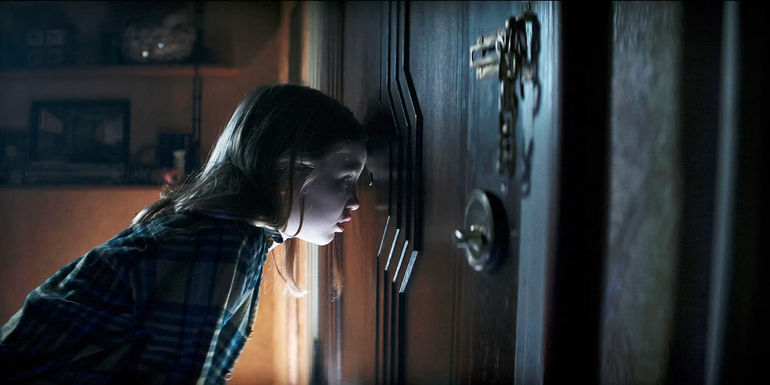 Kassie looking at a door in Evil Dead Rise