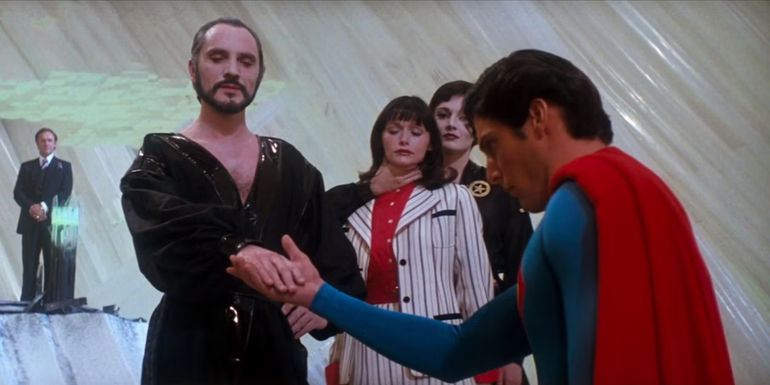 Superman kneeling before General Zod with Lex Luthor, Lois Lane, and Ursa in the background in Superman II.