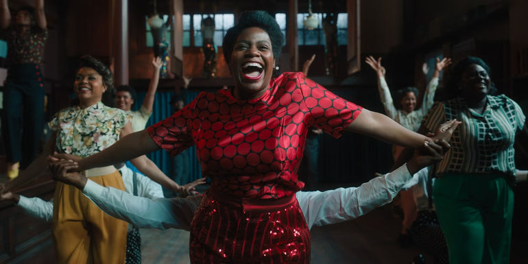 Celie (Fantasia Barrino) smiling and dancing in a red outfit in The Color Purple (2023).