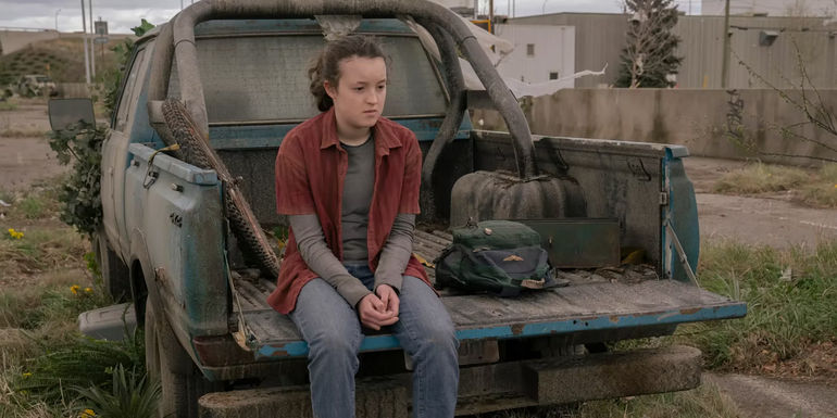 Bella Ramsey as Ellie sitting on the edge of a truck in The Last of Us season 1