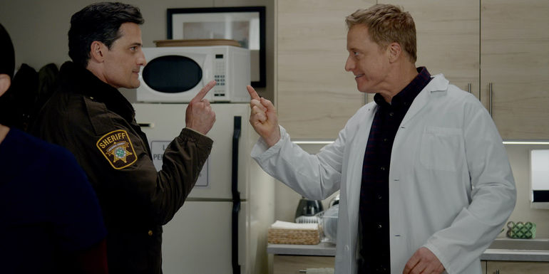 Enver Gjokaj as Joseph Rainier and Alan Tudyk as Harry Vanderspeigle pointing their fingers at each other in Resident Alien season 3.