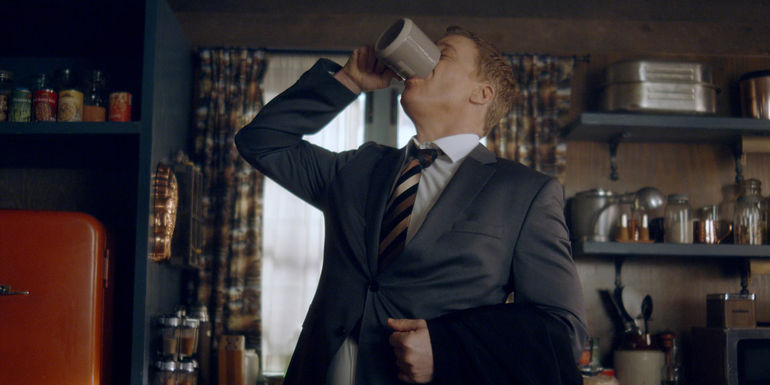 Alan Tudyk as Harry Vanderspeigle drinking from a coffee cup in Resident Alien season 3.