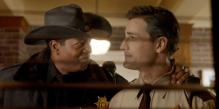 Corey Reynolds as Sheriff Mike Thompson looking at Enver Gjokaj as Joseph Rainier in Resident Alien season 3.