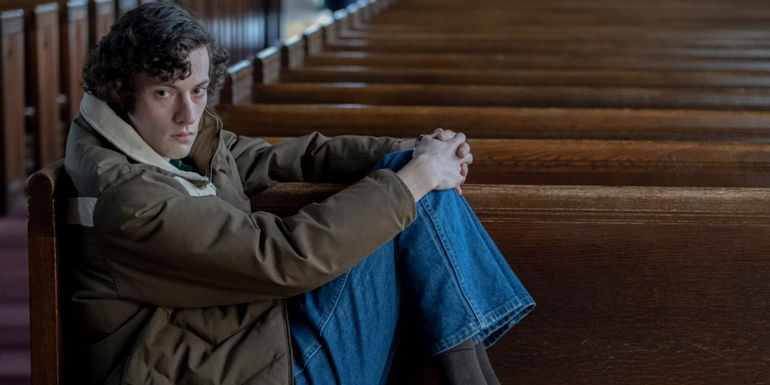 Dominic Sessa as Angus Tully sitting in a chapel in The Holdovers