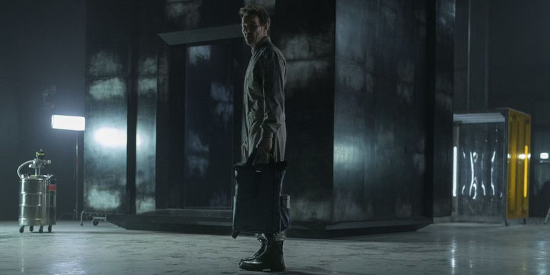 Joel Edgerton as Jason Dessen standing in front of an ominous metal cube and holding a case in Dark Matter