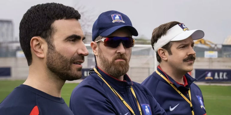 Brett Goldstein as Roy, Brendan Hunt as Coach Beard, and Jason Sudeikis as Ted on the pitch in Ted Lasso