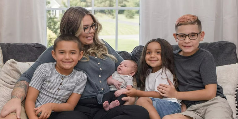 Teen Mom star Kailyn Lowry sits on a couch with sons Lincoln, Creed, Lux, and Isaac (Left-to-right).